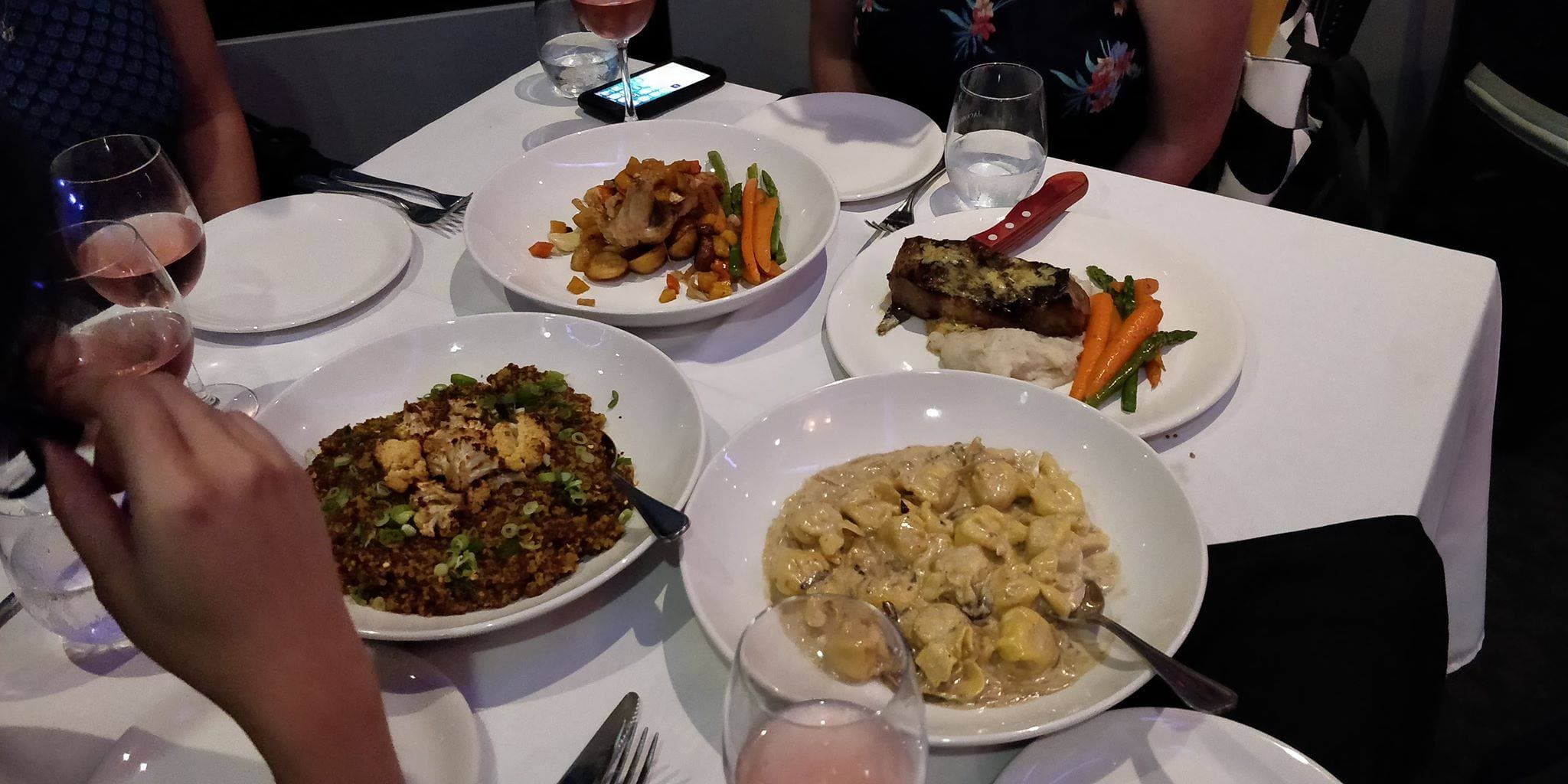 Four full dinner plates appearing on a white tablecloth